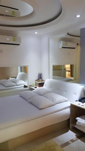 a large white bed in a room with mirrors at Studio Motel (Adult Only) in Santos