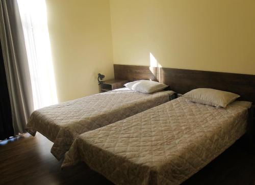 a hotel room with two beds and a window at Hotel Giorgi in Tskaltubo