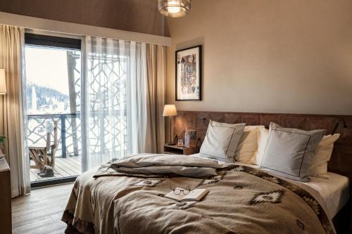 a bedroom with a bed and a large window at Valsana Ferienwohnungen Arosa in Arosa