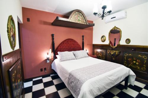 a bedroom with a bed with red walls and a checkered floor at Pousada Estalagem de Brotas in Brotas