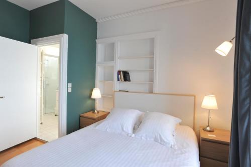 a bedroom with a white bed and a green wall at Gîte de la Plage in Étretat