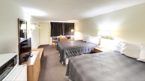 Habitación de hotel con 2 camas y TV de pantalla plana. en Travelers Inn, en Belleville