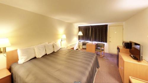 um quarto de hotel com uma cama grande e uma televisão em Travelers Inn em Belleville