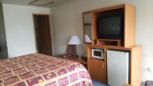 a hotel room with a bed and a flat screen tv at Milwaukie Inn Portland South in Milwaukie