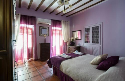 a bedroom with a bed with purple walls and windows at Casa Las Cadenas in Úbeda