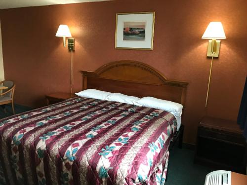 Economy Inn في فورت واين: غرفه فندقيه بسرير ومصباحين