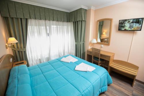 a hotel room with a blue bed and a desk at Hotel PAYRO in Santiago de Compostela