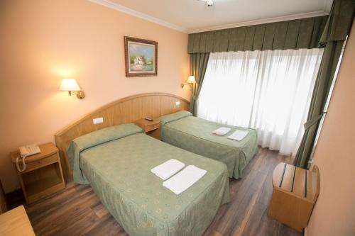a hotel room with two beds and a window at Hotel PAYRO in Santiago de Compostela