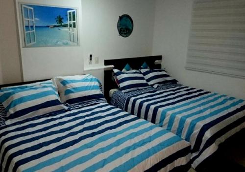 dos camas sentadas una al lado de la otra en una habitación en Apartamento con Piscina En el Rodadero Santa Marta Colombia, en Santa Marta