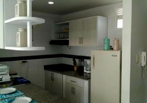 cocina con armarios blancos y nevera blanca en Apartamento con Piscina En el Rodadero Santa Marta Colombia, en Santa Marta