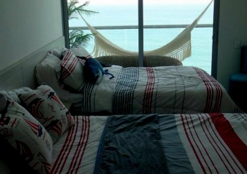 2 camas en un dormitorio con vistas al océano en Apartamento Vacacional En Santa Marta Colombia frente a la Playa, en Santa Marta