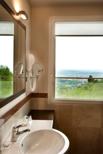 a bathroom with a sink and a mirror and a window at Eden Rock Resort in Florence