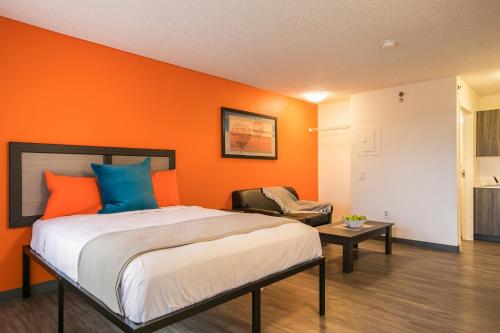 Ce lit se trouve dans un dortoir doté d'un mur orange. dans l'établissement Siegel Select Albuquerque 2, à Albuquerque