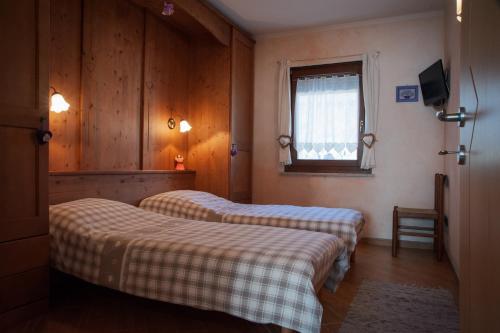 Cette chambre comprend 2 lits et une fenêtre. dans l'établissement Casa Gabriella, à Fiera di Primiero