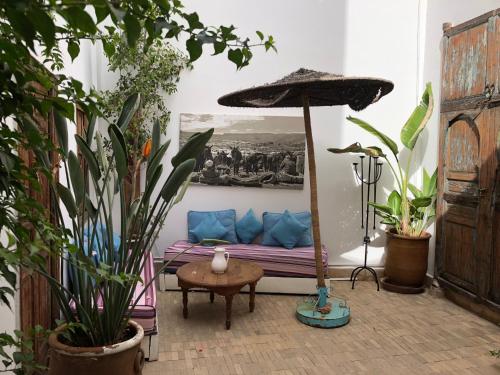 a room with a couch with plants and an umbrella at Riad Le Coq Berbère in Marrakech