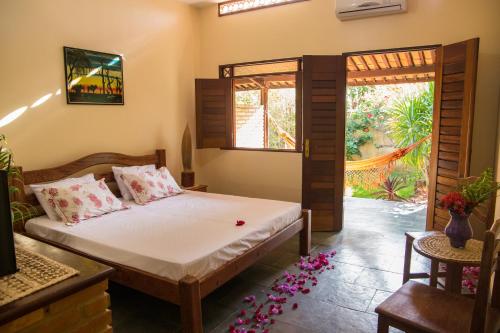 a bedroom with a bed and a door to a garden at Hotel Pousada Arco Iris in Barra de Santo Antônio