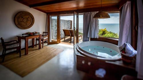 a bathroom with a tub and a dining room with a view at Hotel Sombra e Água Fresca in Pipa