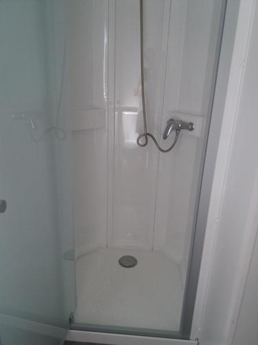 une douche avec une porte vitrée dans une salle de bain dans l'établissement Mobil home 3 chambres, à Canet