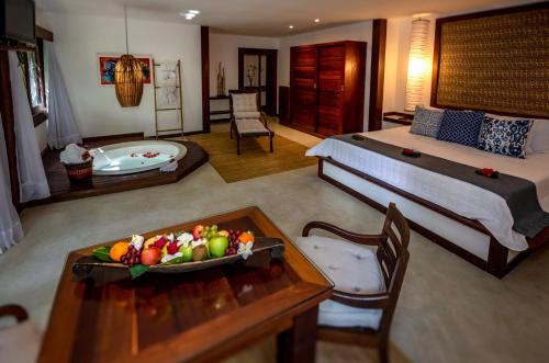 a bedroom with a bed and a table with a bowl of fruit at Hotel Sombra e Água Fresca in Pipa