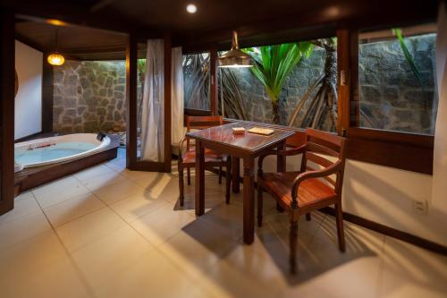a dining room with a table and a bath tub at Hotel Sombra e Água Fresca in Pipa