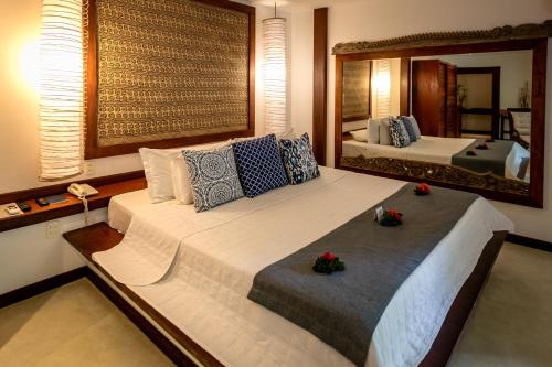 a bedroom with two beds and a large mirror at Hotel Sombra e Água Fresca in Pipa