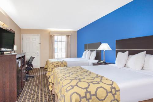a hotel room with two beds and a flat screen tv at Baymont by Wyndham Greenwood in Greenwood
