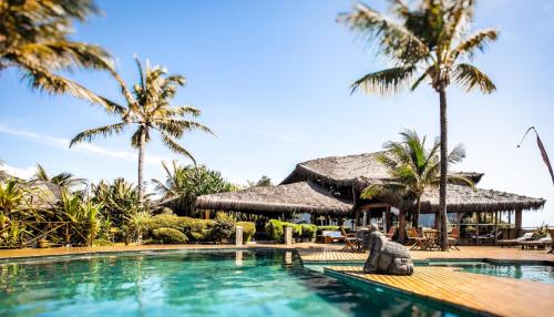 a pool at a resort with a elephant statue in the foreground at Hotel Sombra e Água Fresca in Pipa
