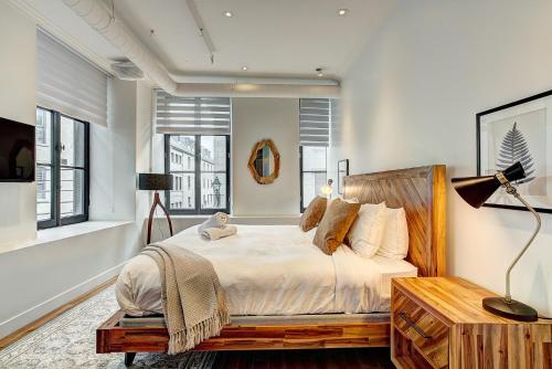 a bedroom with a bed and a desk and windows at Saint Sulpice Lofts by Bakan - Old Montreal in Montréal