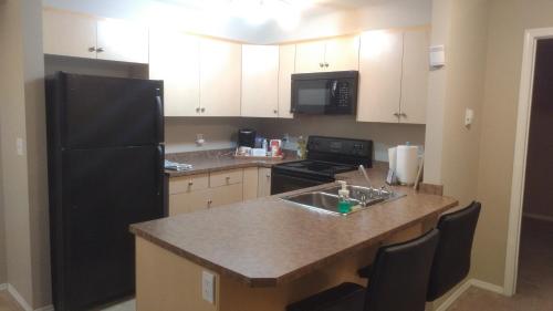 a kitchen with a black refrigerator and a sink at Quiet 2 Bed 2 Bath close to Westview Hospital in Stony Plain