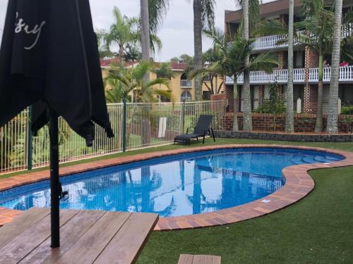 a swimming pool with a chair and an umbrella at Bribie Waterways Motel in Bongaree