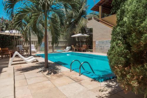 a swimming pool with a palm tree next to a house at Pousada Fortaleza in Canoa Quebrada