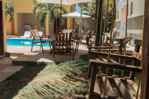 a patio with chairs and an umbrella and a pool at Pousada Fortaleza in Canoa Quebrada