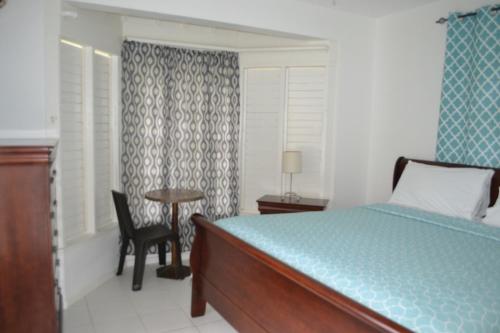 um quarto com uma cama, uma mesa e uma cadeira em Sky Castles Apt H6 em Ocho Rios