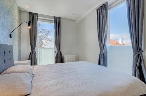 a bedroom with a large bed and large windows at City View Apartment 57 in Vilnius