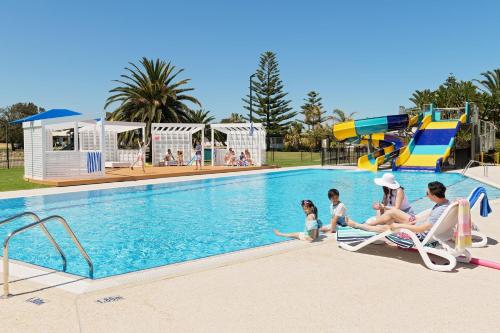 a family sitting in chairs by a swimming pool at The Retreat West Beach Parks in Adelaide