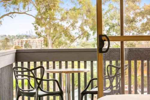 a balcony with two chairs and a table and a window at Nightcap at Shoppingtown Hotel in Doncaster