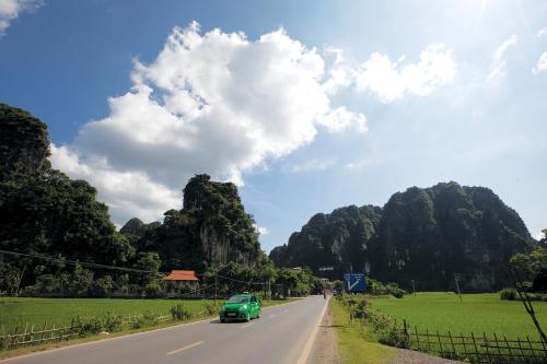 a green car driving down a road with mountains at Hùng Mạnh Plaza Hotel in Hương Tân Lạc