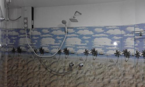 a shower in a bathroom with palm trees on the wall at Coco One Holiday Inn in Mirissa