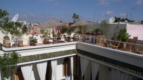 a balcony with tables and chairs on a building at Riad Le Coq Berbère in Marrakech