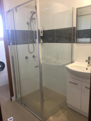 ein Bad mit einer Dusche und einem Waschbecken in der Unterkunft Bridge View Motel in Gorokan