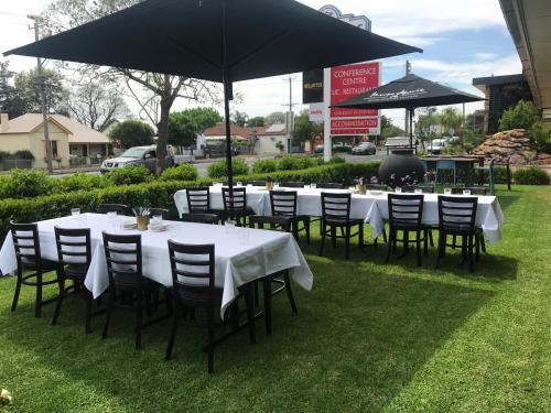 a group of tables and chairs under an umbrella at Cascades Motor Inn in Dubbo
