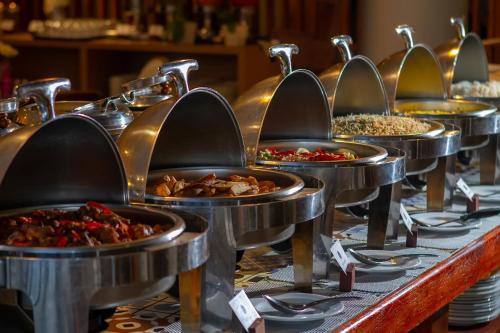 a row of metal pans filled with different types of food at PrimeBiz Hotel Kuta in Kuta