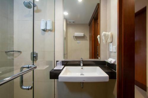 a bathroom with a sink and a glass shower at PrimeBiz Hotel Kuta in Kuta
