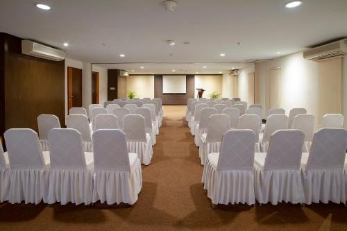 a conference room with white chairs and a podium at PrimeBiz Hotel Kuta in Kuta