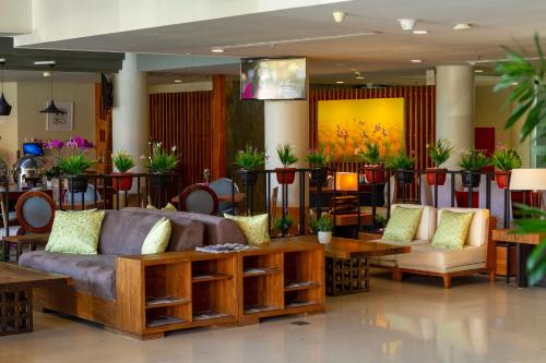 a living room with couches and tables and plants at PrimeBiz Hotel Kuta in Kuta