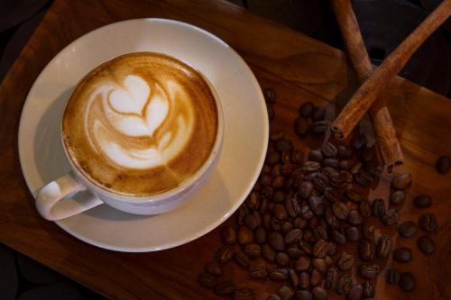a cup of coffee on a plate with coffee beans at PrimeBiz Hotel Kuta in Kuta