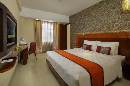 a hotel room with a large bed and a desk at PrimeBiz Hotel Kuta in Kuta