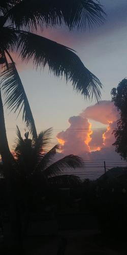 a sunset with palm trees in front of the ocean at Khao Tao Beach Lodge Old Siam in Hua Hin