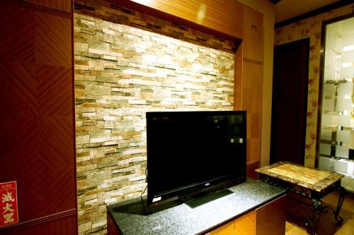 a large flat screen tv on a brick wall at Wen Mei Motel in Nantou City