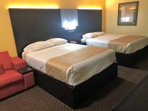 um quarto de hotel com duas camas e uma cadeira em Travelodge by Wyndham New Braunfels em New Braunfels